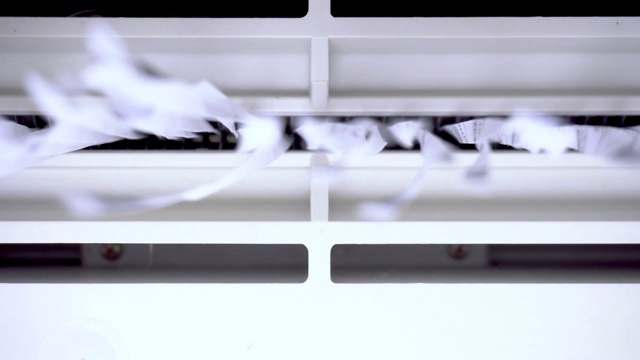 剪纸掉在相机上。碎纸机破坏特写纸。碎纸机把纸切成条状。容器内部视图视频素材