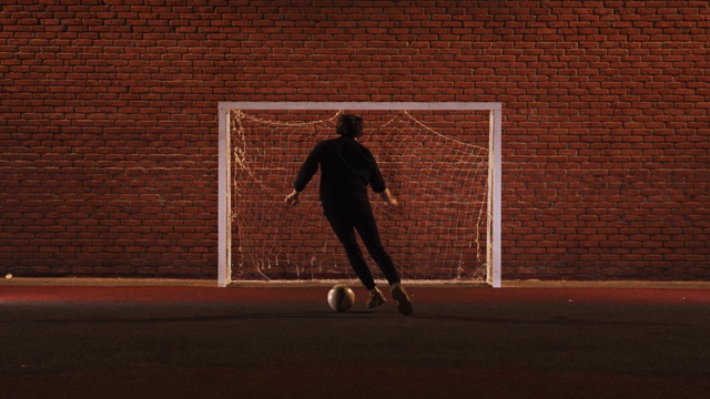 年轻人晚上在操场上踢足球视频下载