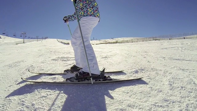 在一个阳光明媚的日子里，一个快乐的年轻女子在滑雪斜坡上下降视频素材