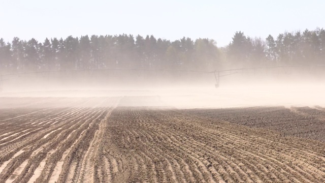 用于工业农田灌溉的雨淋机。犁地风尘。沙尘暴发生在干燥的田间，受气候变化的影响。犁地和播种地的平行线视频下载
