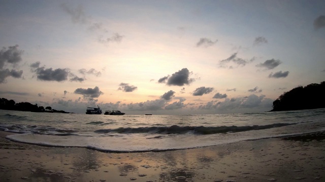 时间流逝的运动，海浪击中海滩和船背景云移动快，金色的光日出在早晨的天空视频下载