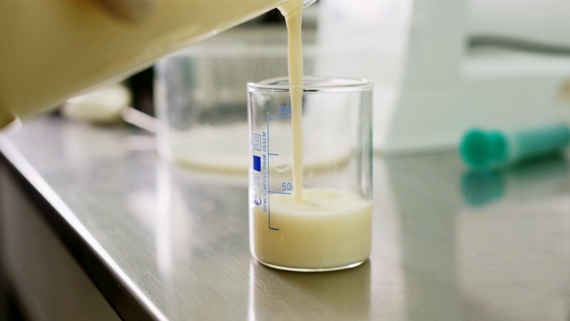 助手将牛奶倒进烧杯检查桌上的牛奶质量视频下载