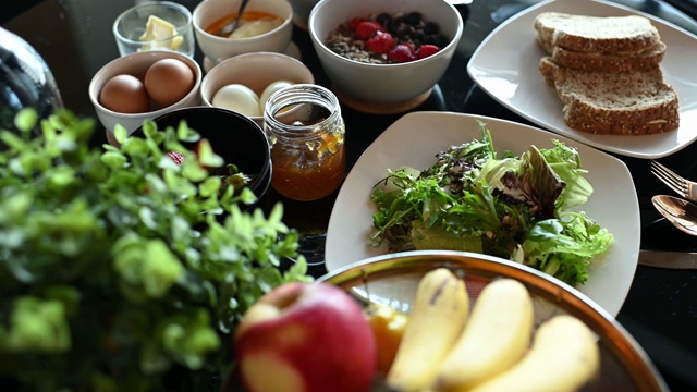 健康的早餐，水果橙，草莓，蔬菜，香蕉，鸡蛋，烤面包，酸奶苹果和果酱在餐桌上视频素材
