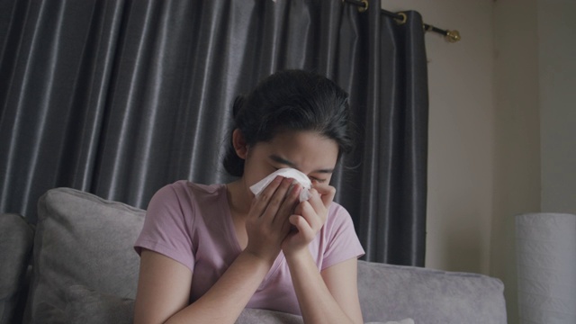 亚洲青少年打喷嚏，擤她的鼻子与餐巾流感。她过敏。年轻。女孩感冒在家视频素材