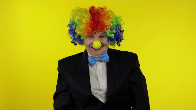 老小丑戴着五颜六色的假发微笑着，做着傻乎乎的鬼脸，胡闹着视频下载