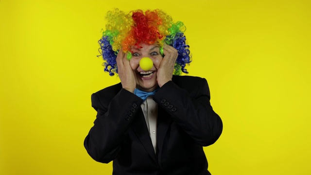 年长的小丑老妇人戴着五颜六色的假发看起来很惊讶很震惊。惊讶的是视频下载