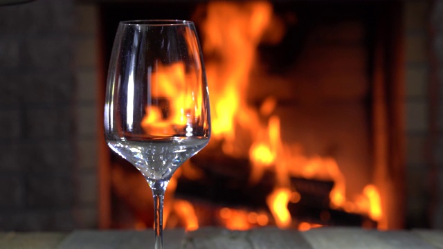 冬天，在乡村别墅舒适的壁炉前，红酒倒进玻璃杯里。视频下载