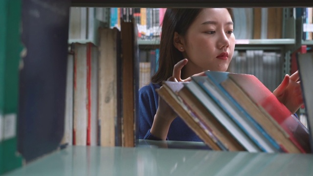 一个亚洲女人在图书馆找书视频素材