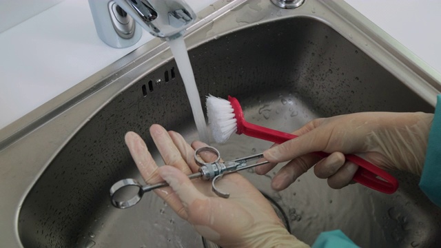 特写的手在手套下清洗牙科医疗器械下的自来水视频素材