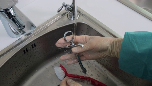 特写护士的手在蒸馏水下清洗牙科工具视频素材