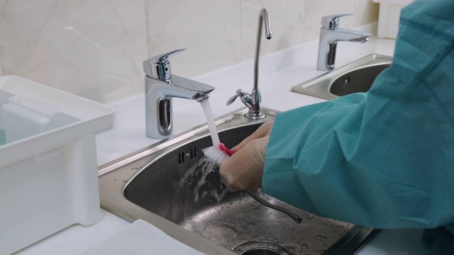 医生用刷子在自来水下清洗医疗工具的中镜头视频素材
