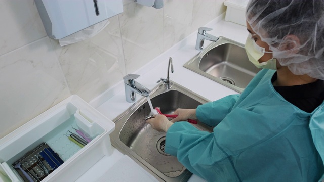医生在水流下用刷子清洗牙科器械的宽镜头视频素材