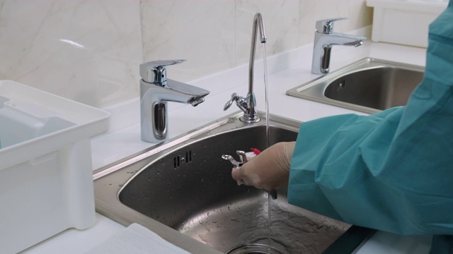 医生在蒸馏水下清洗牙齿工具的中镜头视频素材
