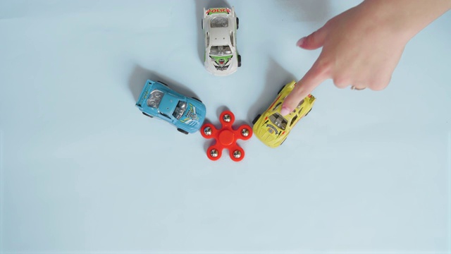 指尖陀螺孤立的蓝色背景与玩具汽车视频下载
