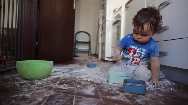 蹒跚学步的男孩在厨房玩面粉视频下载