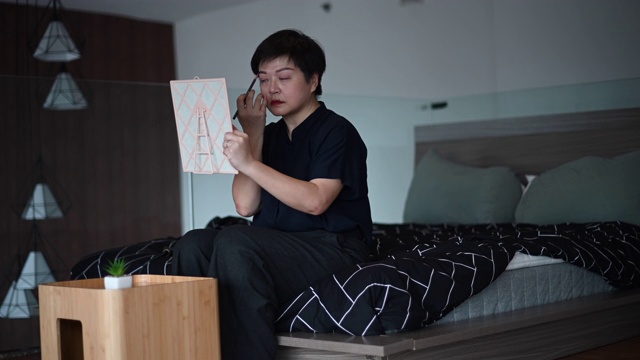 一位亚洲华人中年人正准备在离开她的公寓或画眉毛之前化妆视频素材