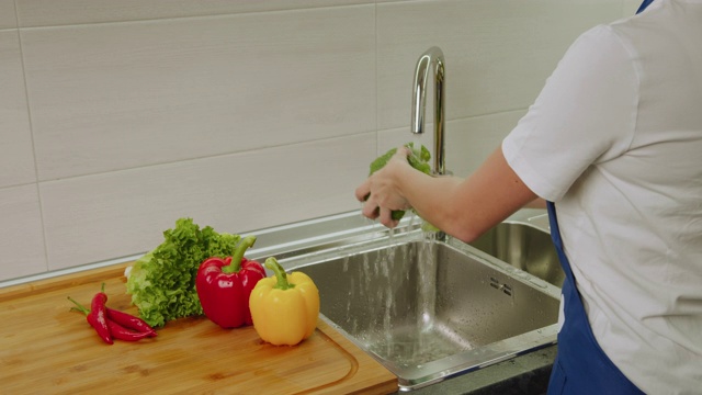 后视图。近距离射击。女人的手在洗脸盆里洗黄椒和花椰菜。4 k视频下载