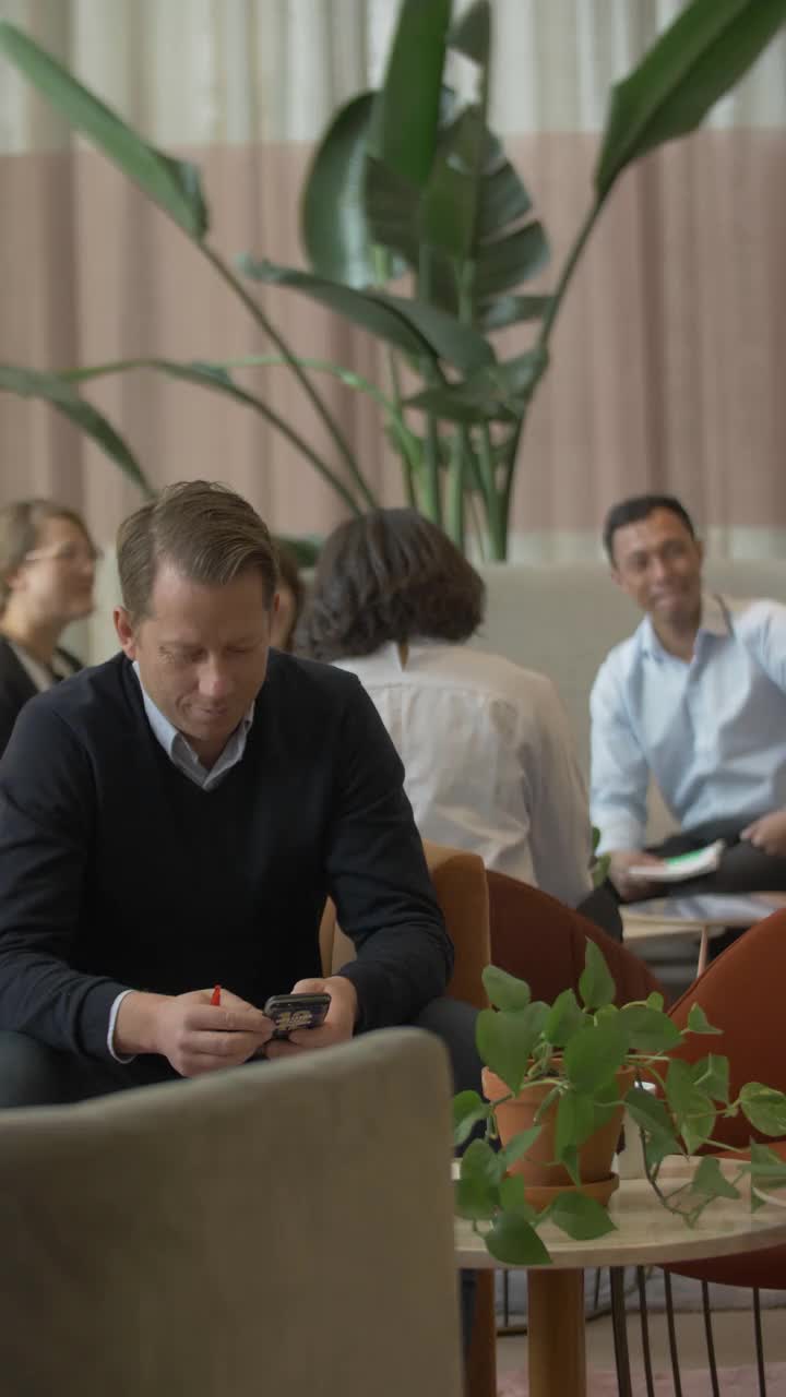 商人使用智能手机，企业家在绿色共同工作空间讨论背景视频下载