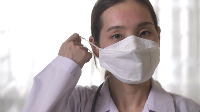 亚洲自信女医生除去她的外科口罩，看着相机视频素材