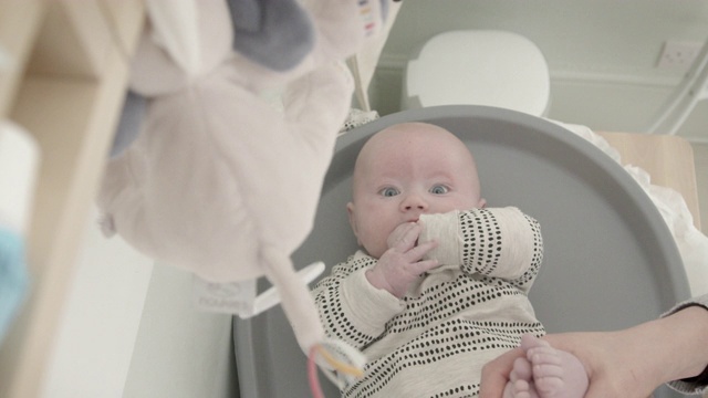 高视角的母亲给可爱的蓝眼睛的男婴在婴儿室换尿布。视频素材