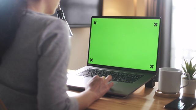 亚洲妇女在家里使用绿色屏幕的笔记本电脑视频下载