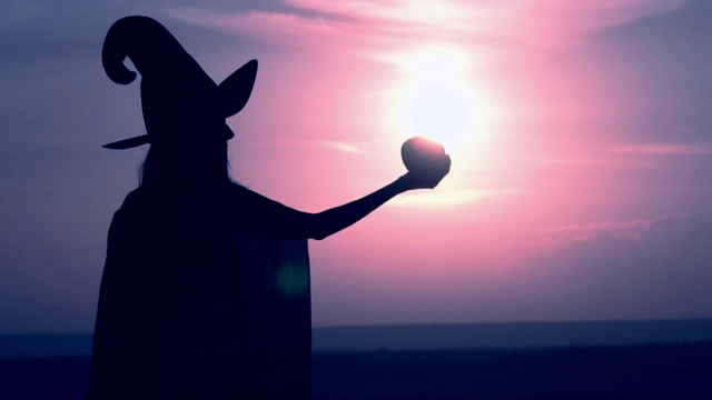 一个穿着女巫服装的女人举起一个有魔力的苹果视频素材