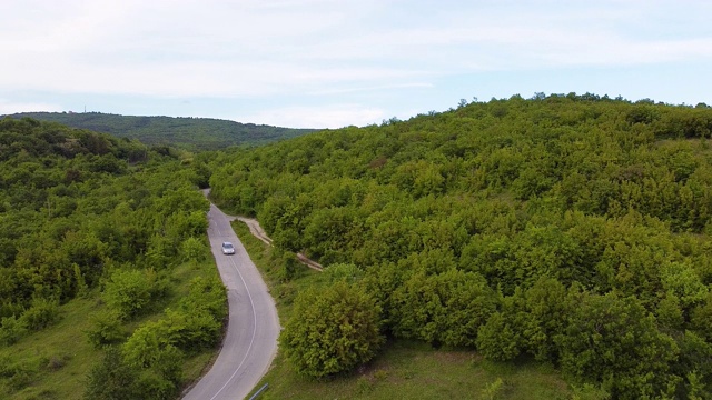 在森林中空旷的乡村道路上行驶的汽车。空中无人机视图视频素材