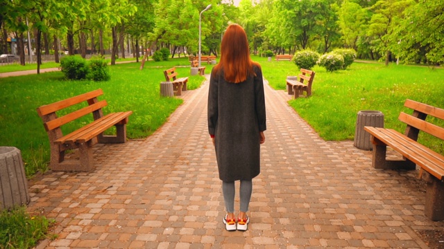 一个红头发的陌生女人在公园里散步视频素材