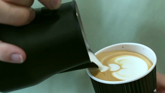 咖啡师把牛奶倒进咖啡里。视频下载