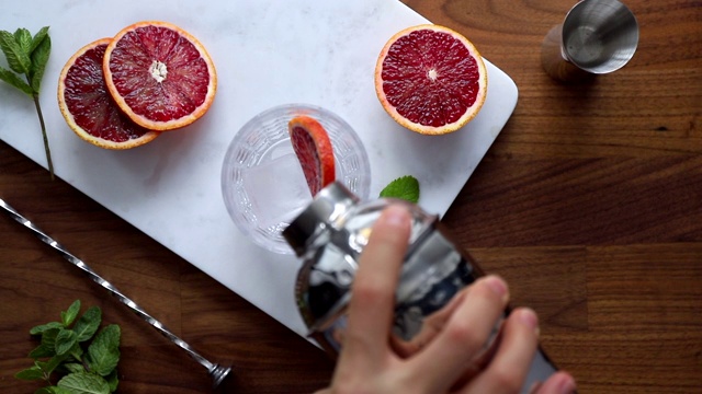 将调酒器中的血橙倒入清凉的夏日鸡尾酒中视频素材