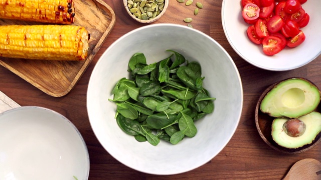 向碗中加入新鲜菠菜。健康饮食理念，用蔬菜制作健康的夏季沙拉。从以上观点。视频下载