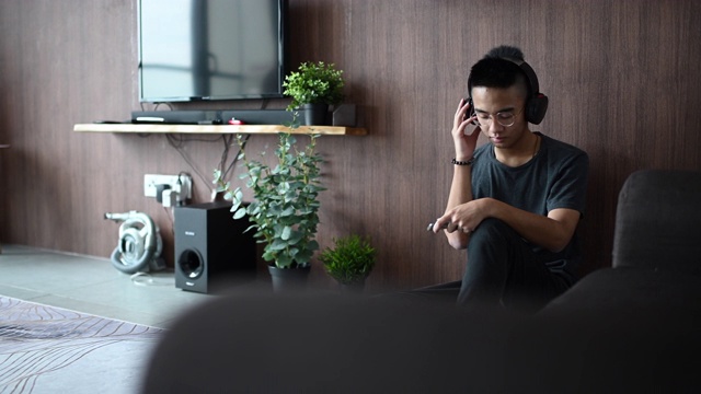 一个亚裔中国少年用耳机听音乐视频素材