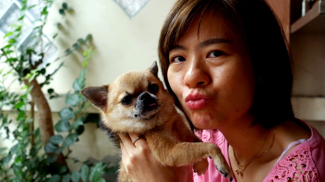 中景:亚洲短发妇女抱着一只狗在房子前玩耍视频下载