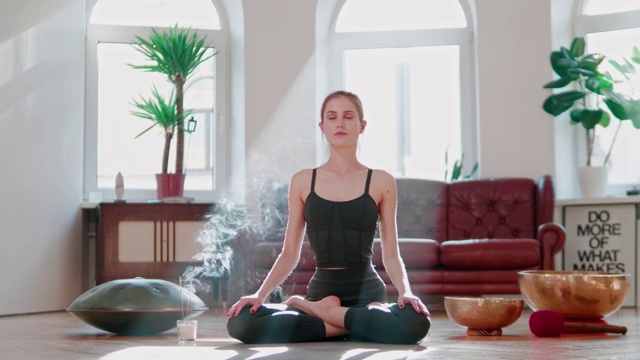 积极的女孩在家里坐在地板上练习瑜伽冥想。禅瑜伽。视频下载