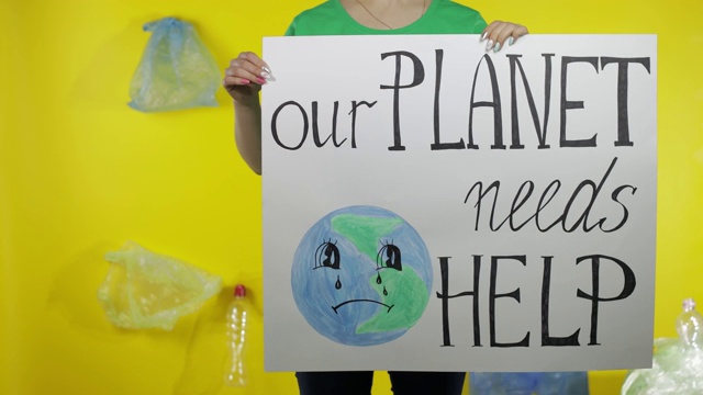 一个不认识的女人举着抗议海报“我们的星球需要帮助”。塑料污染环境视频素材