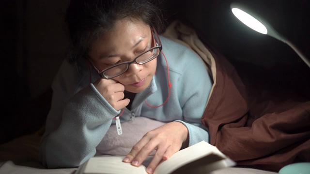 2多莉拍摄的亚洲妇女晚上在床上看书视频素材