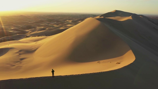 日落时分从沙丘上俯瞰戈壁沙漠的人的鸟瞰图视频下载