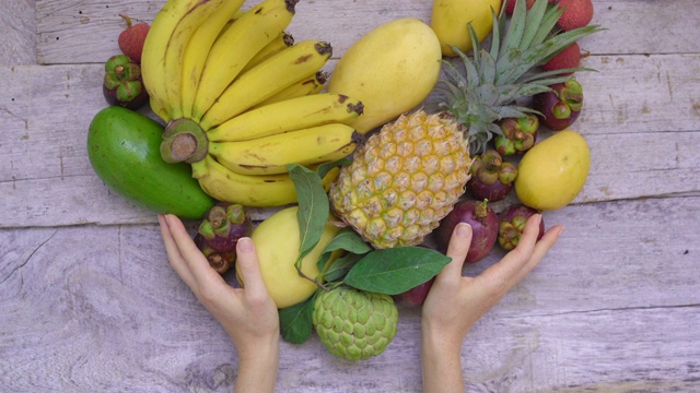 俯视-一个女人的手拿着一颗心，由许多热带水果视频下载