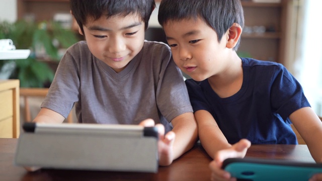 男孩子们在看平板电脑和智能手机视频素材