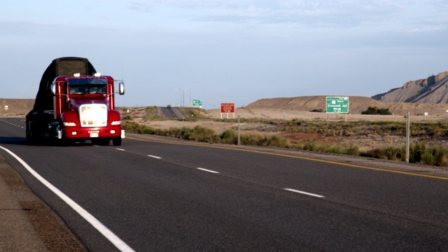 一辆长途半卡车和拖车在沙漠的四车道公路上行驶在黎明或黄昏视频下载