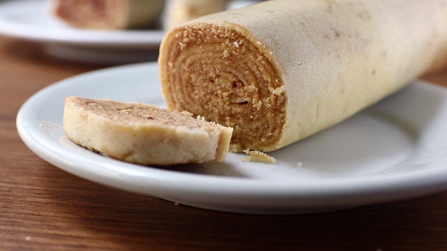 在切罗洛之火。将巴西甜点Bolo de Rolo(瑞士卷，卷饼)切成薄片，放在白色的盘子上，以木材为背景视频素材