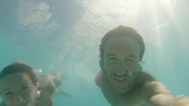 一对年轻夫妇在热带泻湖水下游泳的自拍。两个人玩着水下摄像机拍摄他们的假期。慢动作视频素材