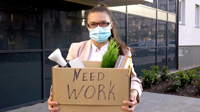 戴医用口罩的女商人举着“需要工作”的牌子。新冠肺炎大流行导致的失业视频下载