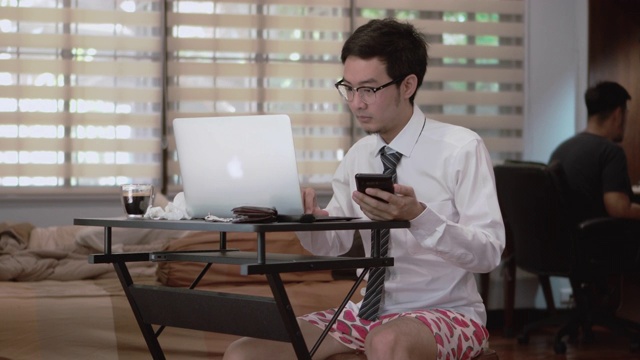 亚洲男人在家工作，而家人在房间里视频下载