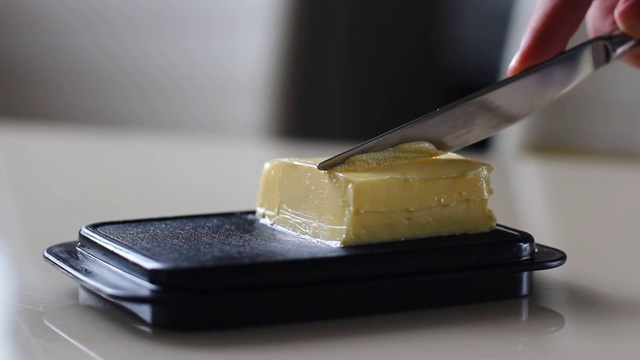 一个男人用刀在桌上拿黄油做三明治视频下载