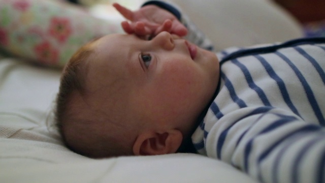 漂亮可爱可爱的宝宝躺在床上。新生婴儿的脸视频素材