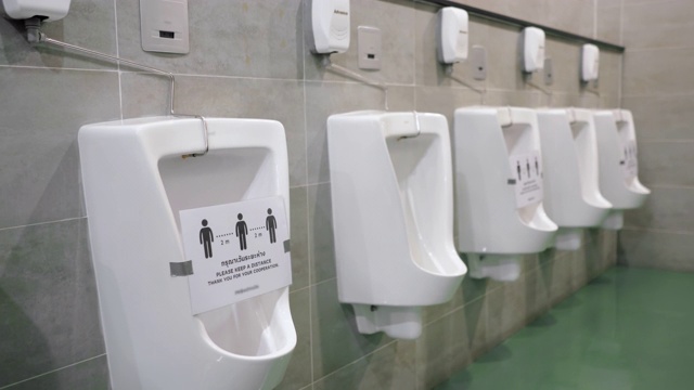 2019冠状病毒大流行期间，带有社交距离标志的男厕小便池视频素材
