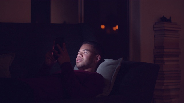 一个晚上在家玩手机的年轻人视频素材