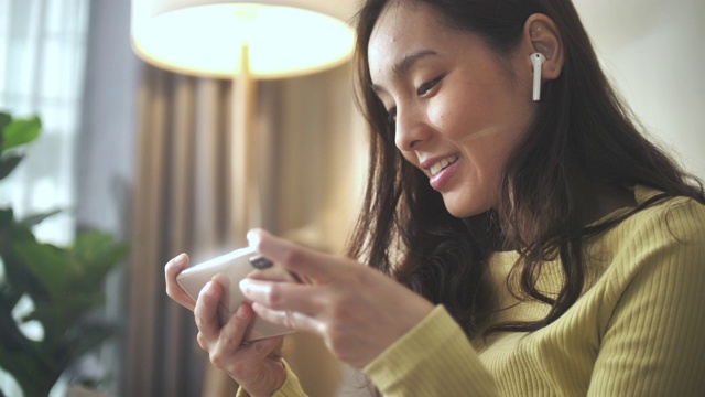 亚洲女性在客厅用智能手机玩网络游戏视频下载