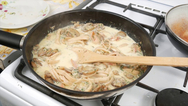 用鱿鱼和蘑菇烹饪奶油酱，在平底锅里加奶油，特写视频素材